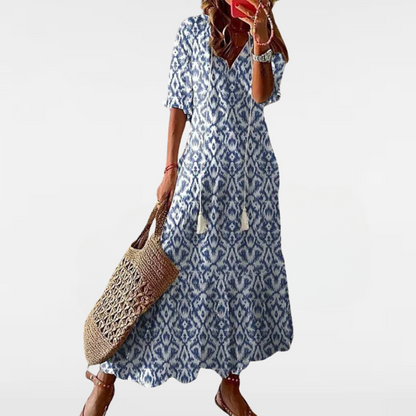 Blue patterned bohemian dress with short sleeves, tassel detail, and flared midi hem.