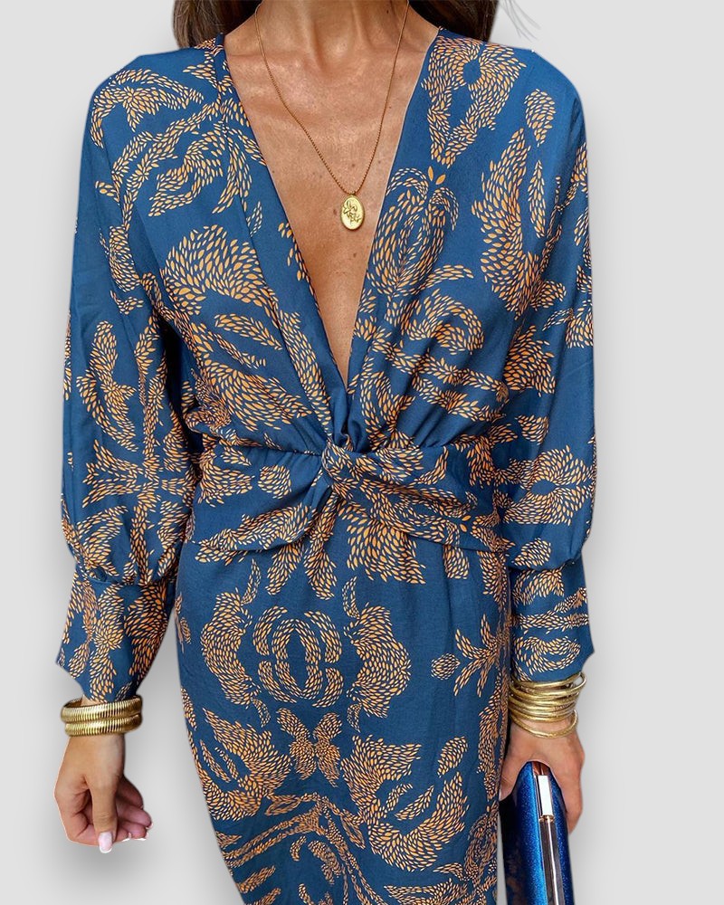 Blue V-neck wrap dress close-up with long sleeves, gold tie waist, and ornate leaf print.