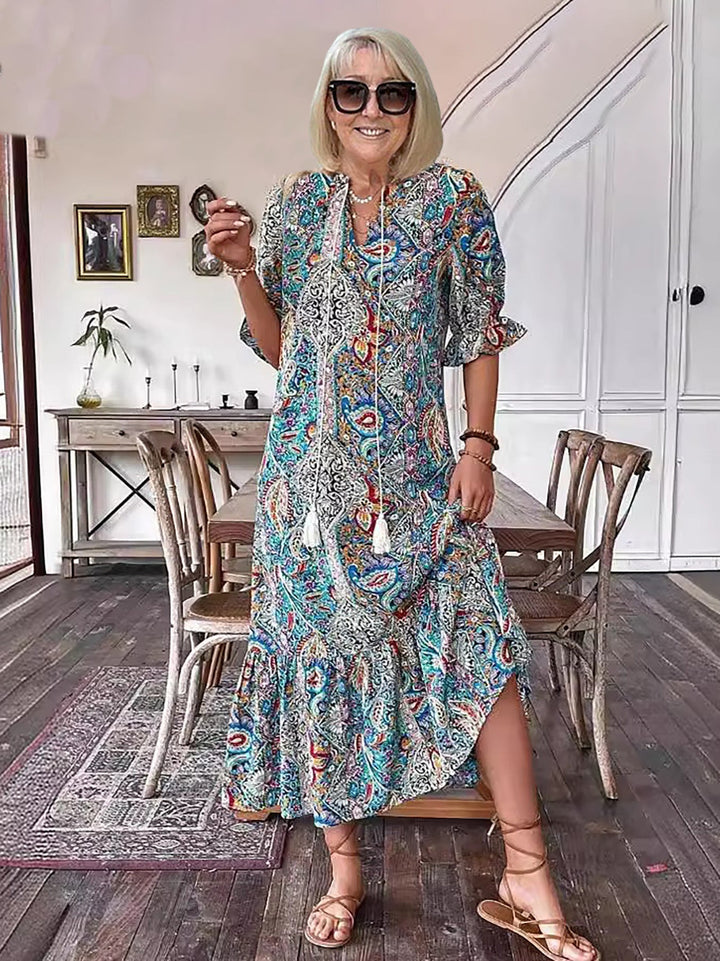 Boho grace dress in teal and blue paisley print with tassel-trimmed neckline and tiered skirt