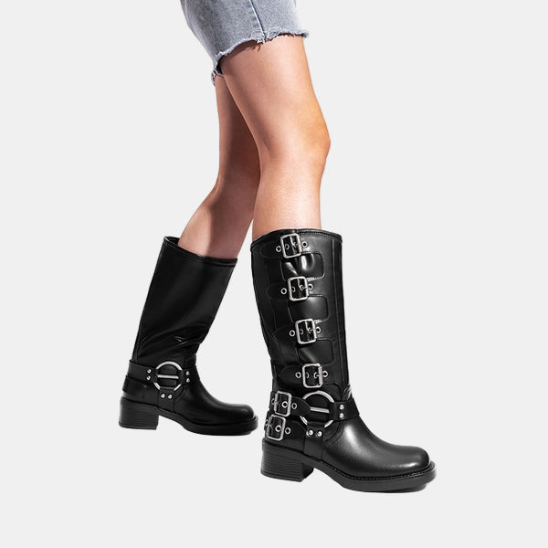 Knee-high leather boots in black worn with cuffed denim and buckle side straps