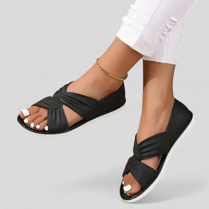 Black orthopedic sandals on white outsole with open toe and knotted cross strap
