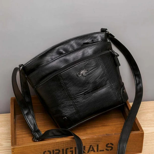Black leather crossbody bag with zip compartments, kangaroo logo, and crossbody strap.