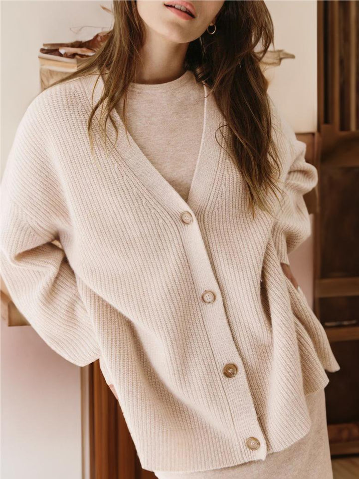 Oatmeal knit cardigan with V-neck and button front, relaxed cocoon silhouette, ribbed trim.