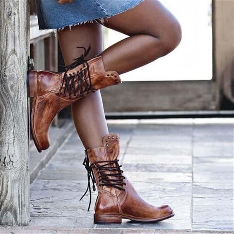 Brown leather lace-up boots with studded cuff and scuffed vintage finish.