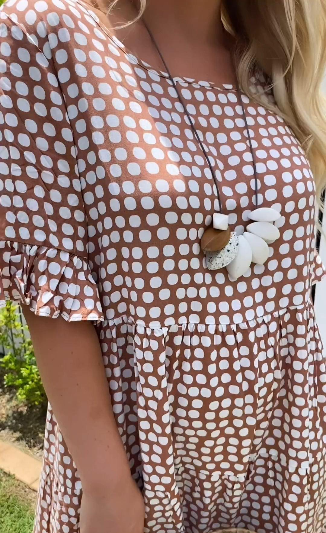 Brown dot-print dress detail with white flower applique and puff sleeves