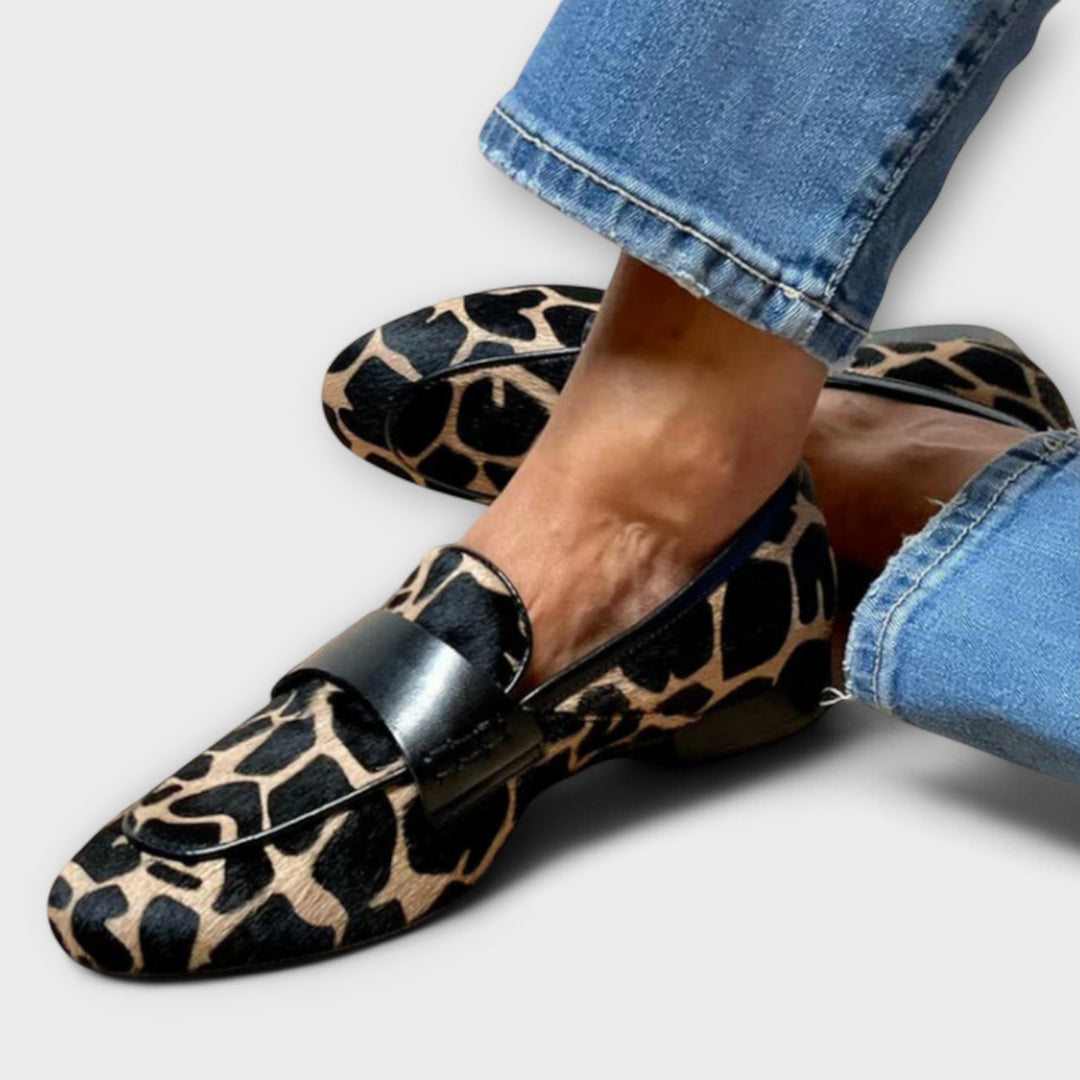 Leopard-print slip-on slippers with black buckle strap detail, pointed toe.