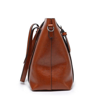 Women’s brown leather crossbody bag with curved shape and shoulder strap ring handles