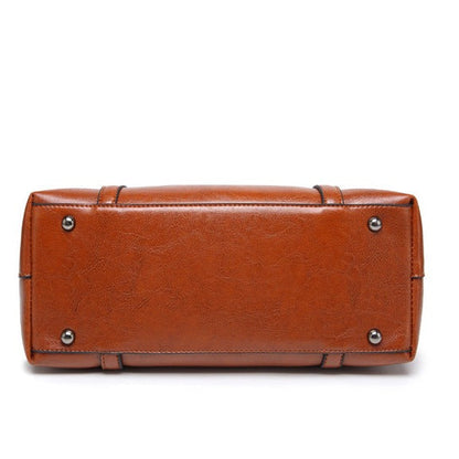 Women’s brown leather crossbody tote bag with metal studs and structured top edge