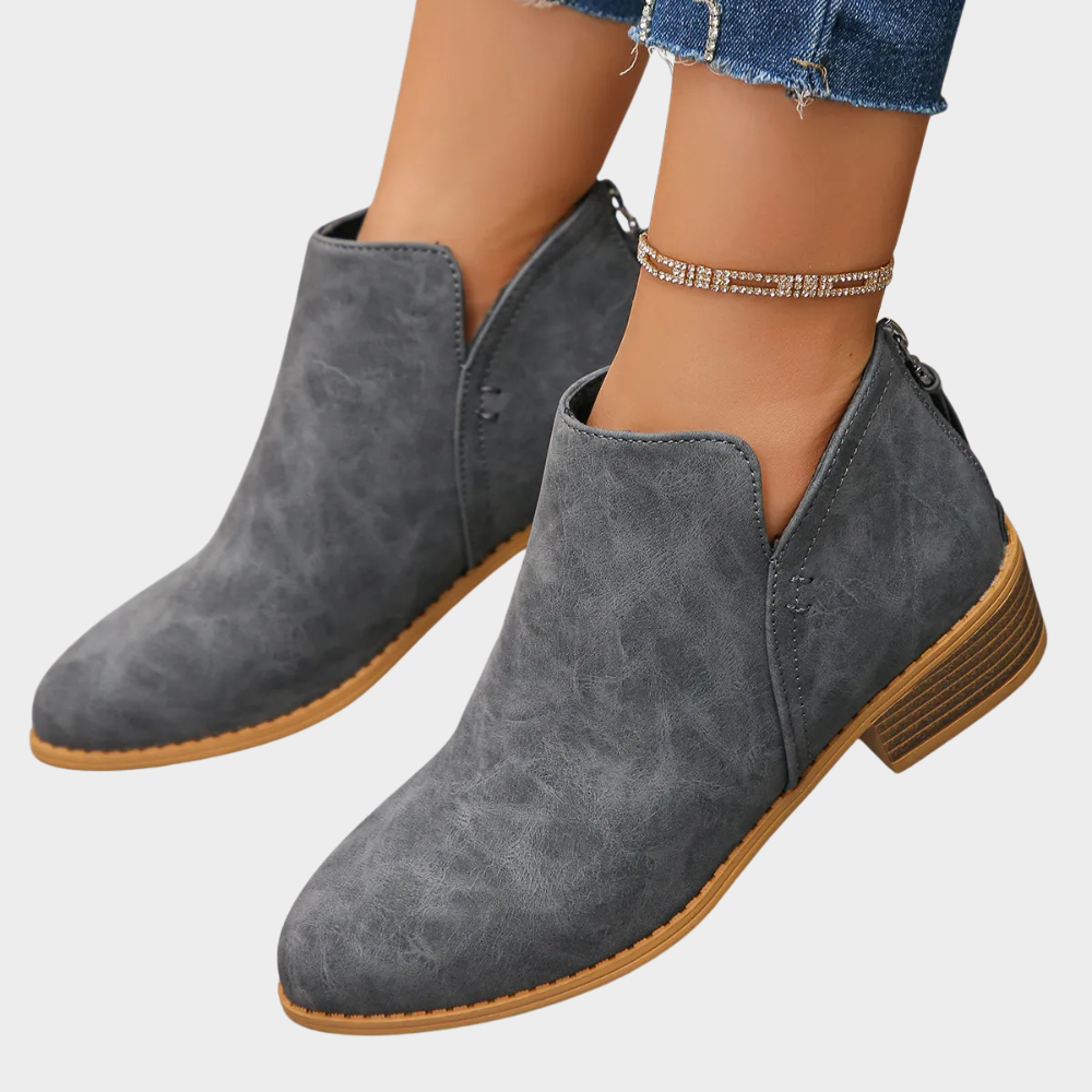 Gray suede low-heel ankle boot with side zipper and tan textured outsole