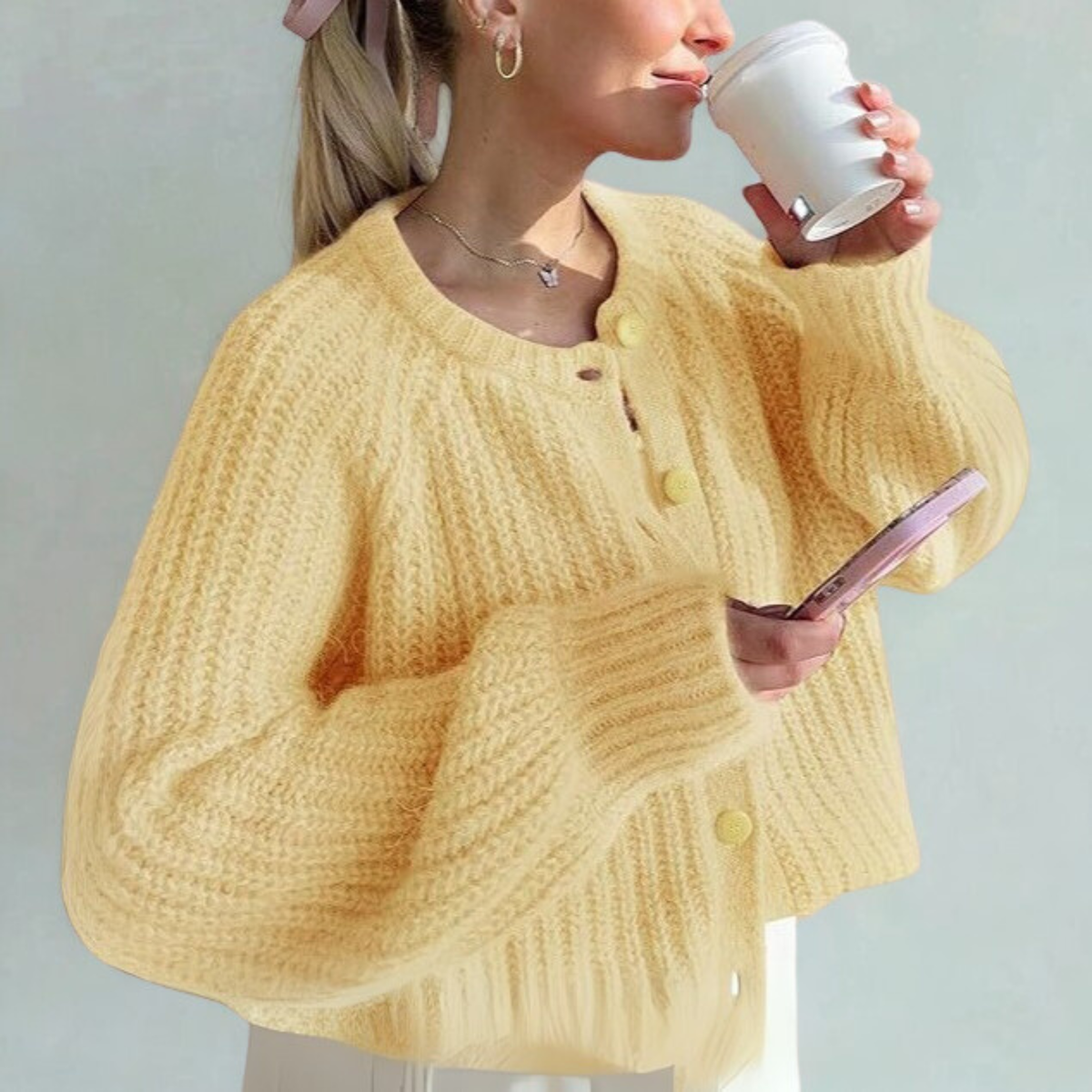 Yellow knit cardigan sweater with round neck, long sleeves, and front button placket