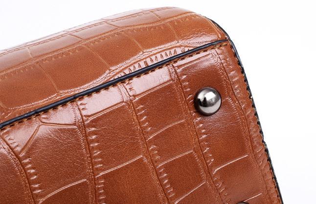Brown crocodile-pattern handbag flap with round metal snap and stitched edge
