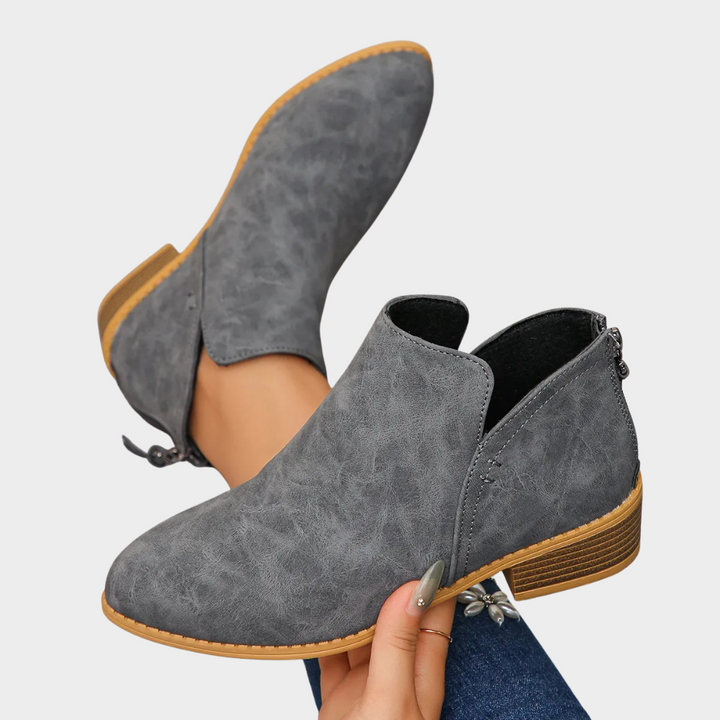 Gray suede low-heel ankle boot, side angle with tan outsole edge trim