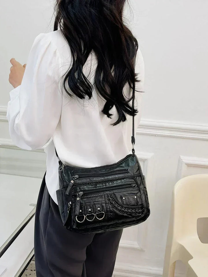 Black multi-layer crossbody bag worn on a model with front mini-zip pocket