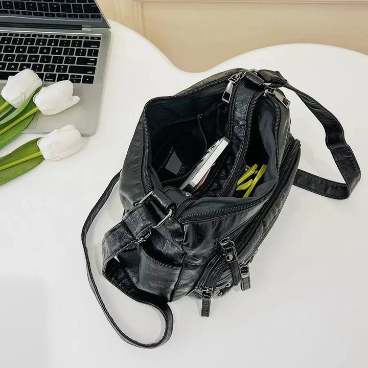 Black multi-layer crossbody bag open with inner compartments and zipper closure