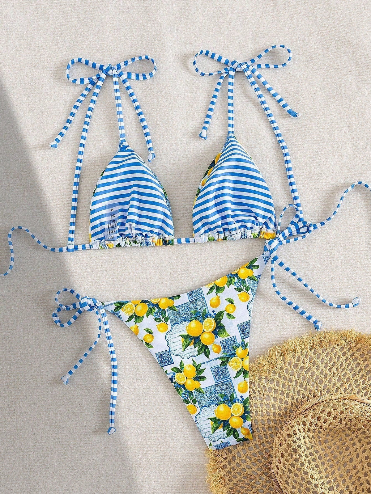 Lemon-print triangle bikini set with blue striped ties, laid out