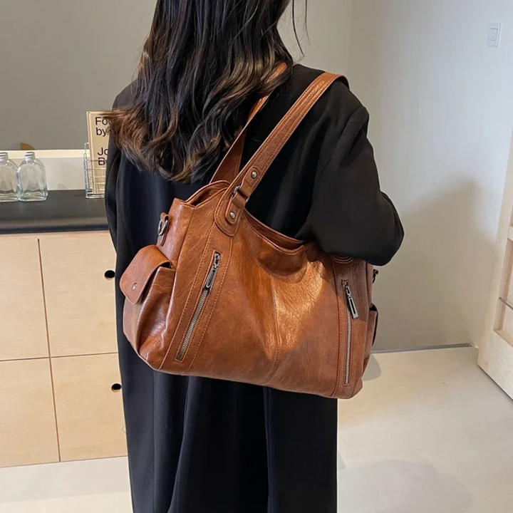 Brown large shoulder bag with handles and crossbody strap; dual zip pockets on front