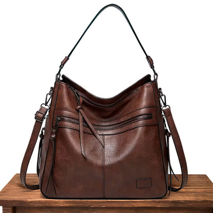 Brown hobo shoulder bag with front zip pockets, tassel detail, and top handle straps