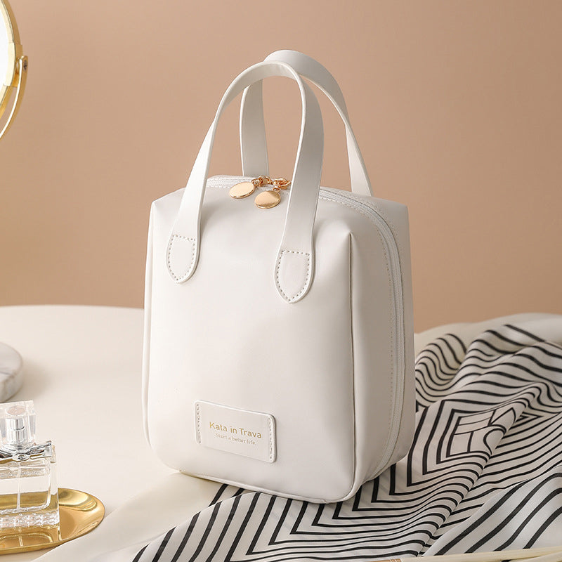 White travel bag tote with top handles, gold charm, and front label pocket