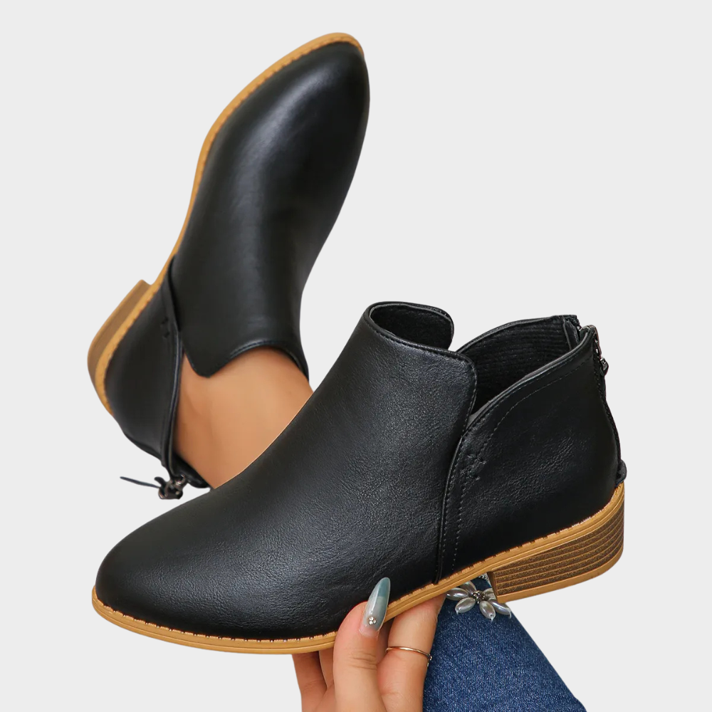 Black low-heel ankle boot with side tie and tan outsole trim
