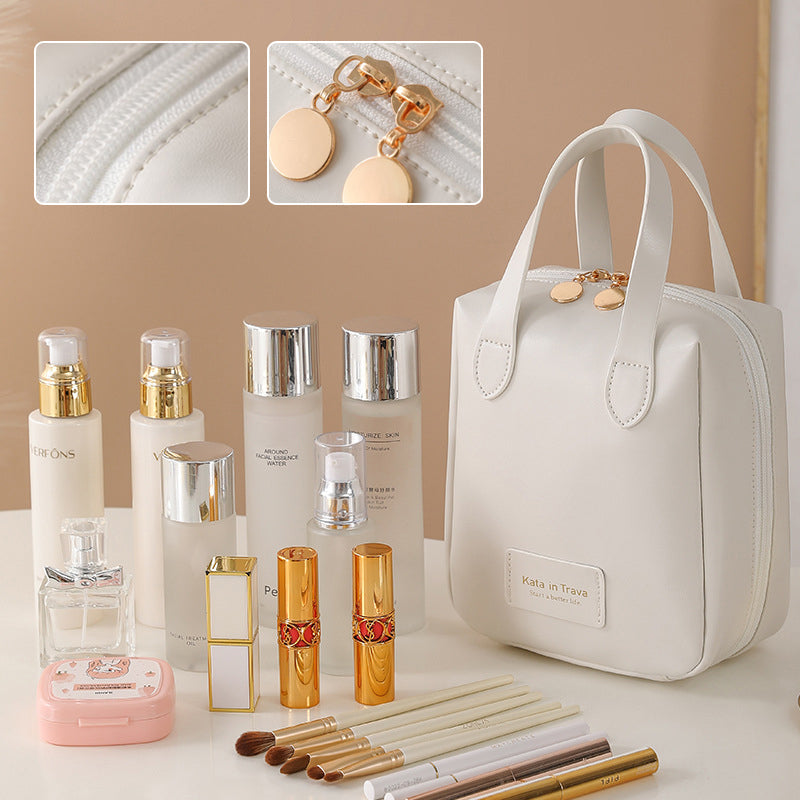 White travel bag with gold zipper charm and stitched handle detailing