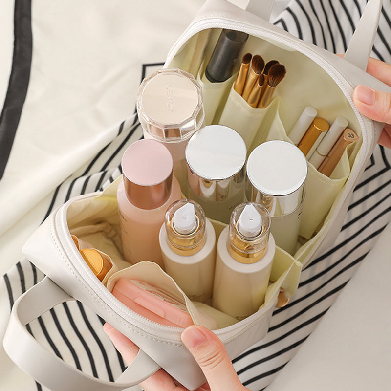 White travel bag open with skincare bottles, powders, and makeup brushes
