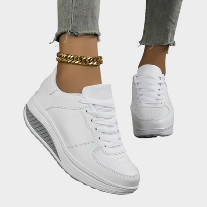 White orthopedic sneakers with lace-up, stitched panel detailing, and chunky cushioned sole