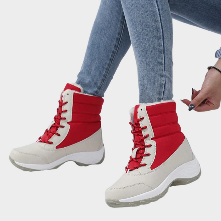 Red-and-cream winter boots with lace-up front, faux-fur cuffs, and chunky tread sole.