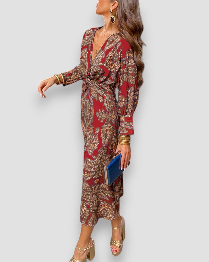 Red V-neck wrap dress with long sleeves, patterned button-tie waist, and ornate print.
