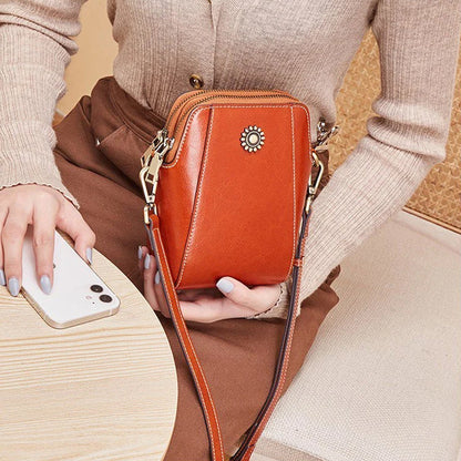 Orange mini crossbody handbag with zipper and sunburst emblem