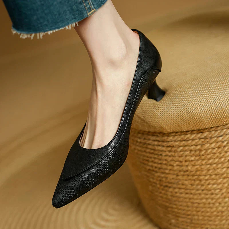 Black pointed-toe pumps with low block heel worn with denim cuff.