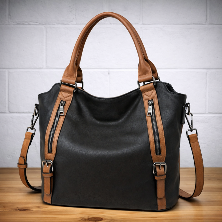 Black leather hobo tote bag with brown trim, dual zip pockets, and crossbody strap