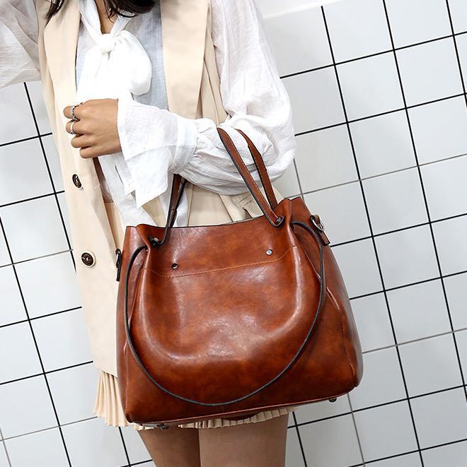 Brown women’s retro tote bag with rounded handle straps; matching wallet in set.