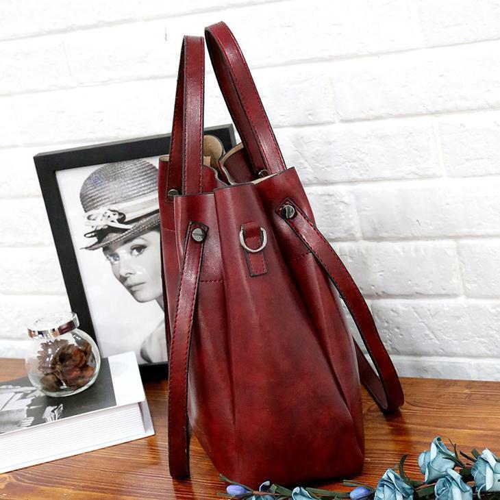 Burgundy tote bag with shoulder straps, front tab details, and side pockets