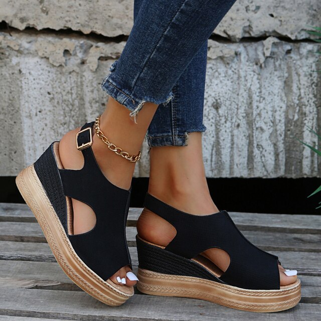 Black wedge sandals with peep-toe cutouts and ankle strap with gold buckle