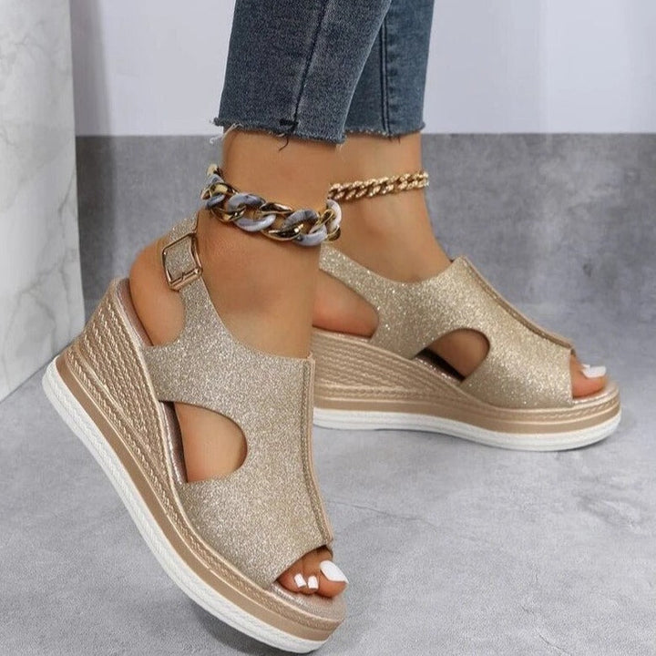 Gold glitter wedge sandals with ankle buckle strap, chain detail, and peep-toe cutouts