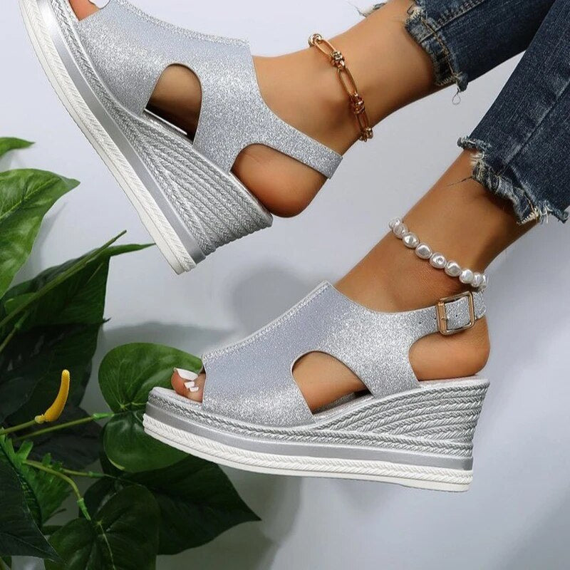 Silver glitter wedge sandals with peep-toe cutouts and ankle buckle strap