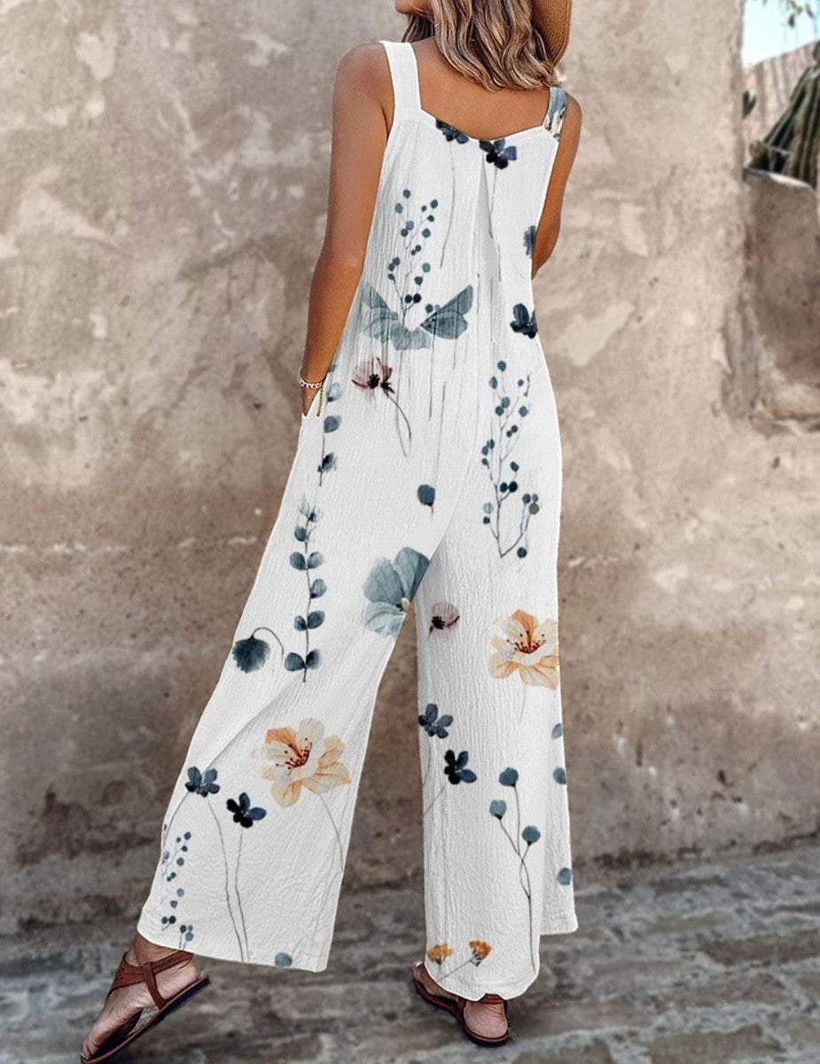 White sleeveless floral printed overalls with blue botanical stems and wide-leg shape.