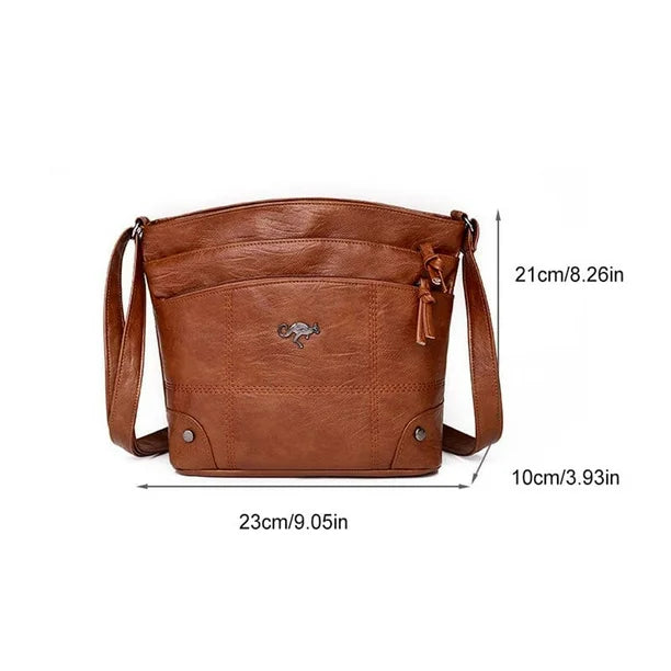 Brown leather crossbody bag with zip top, tassel pull, front logo, and two button pockets.