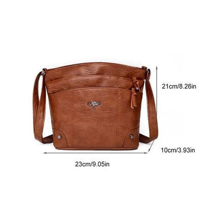 Brown leather crossbody bag with zip top, tassel pull, front logo, and two button pockets.