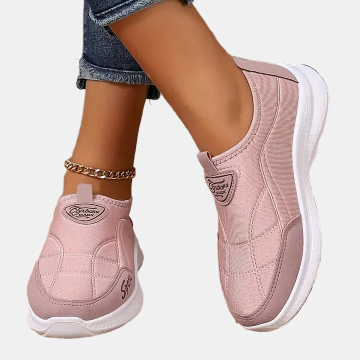 Pink slip-on sneakers with white sole, logo patch, and quilted panel design
