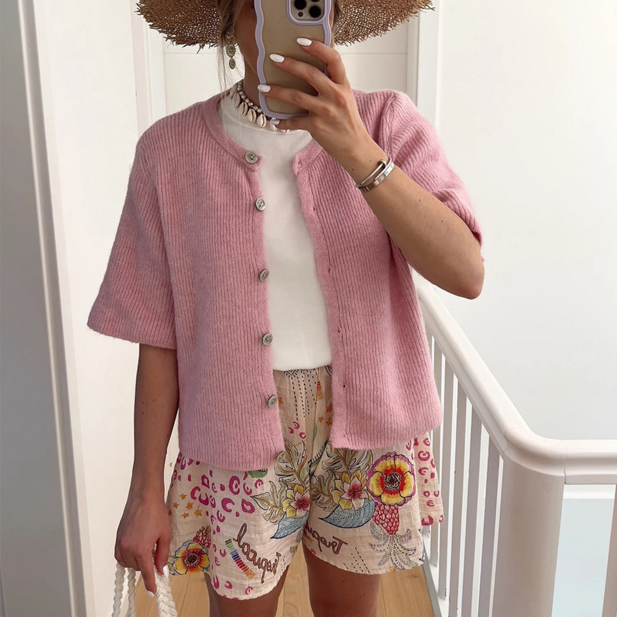 Pink short-sleeve button-front knit cardigan with ribbed texture and rounded collar.