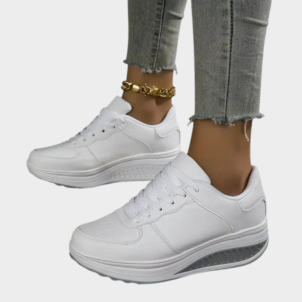 White orthopedic sneakers with lace-up closure, seam detailing, and ribbed platform sole