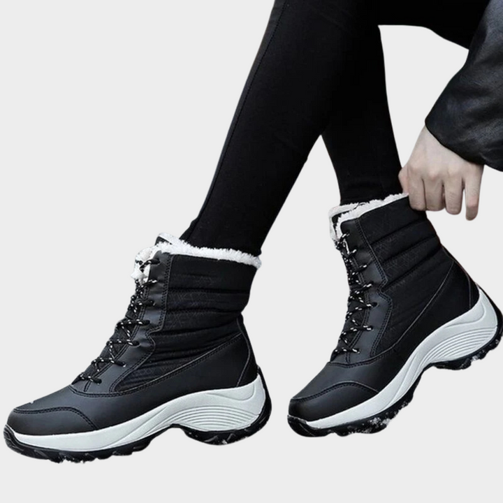 Black winter boots with lace-up front, cushioned collar, white faux-fur cuff, tread sole.
