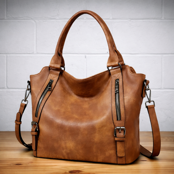 Brown leather hobo tote bag with two top handles, zip pockets, and crossbody strap