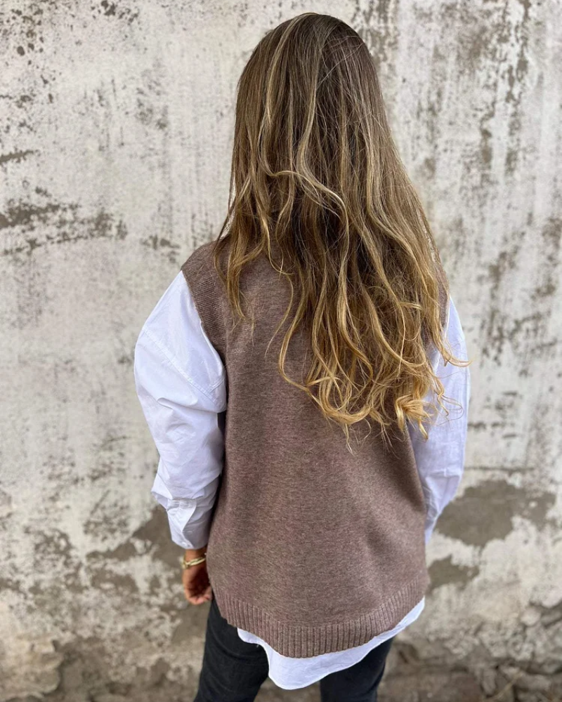 Brown knit sweater vest, V-neck and ribbed hem with white button-down underneath (back view).