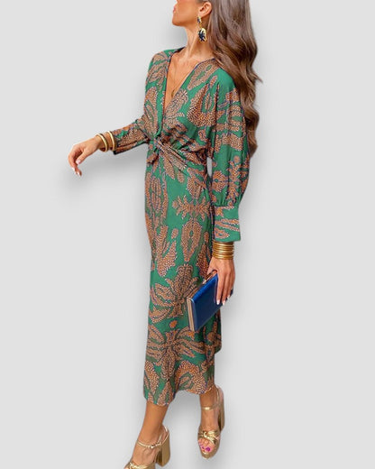 Green V-neck wrap dress with long sleeves, gold tie waist, and ornate leaf print.