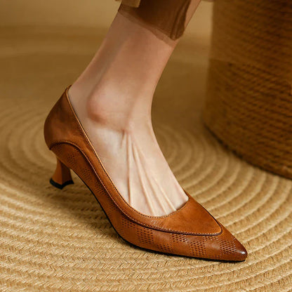 Brown low block heel pumps with perforated texture and slip-on pointed toe.