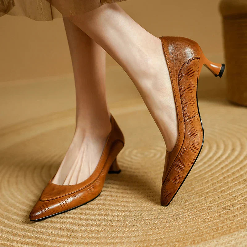 Brown pointed-toe pumps with perforated detailing and a low block heel.