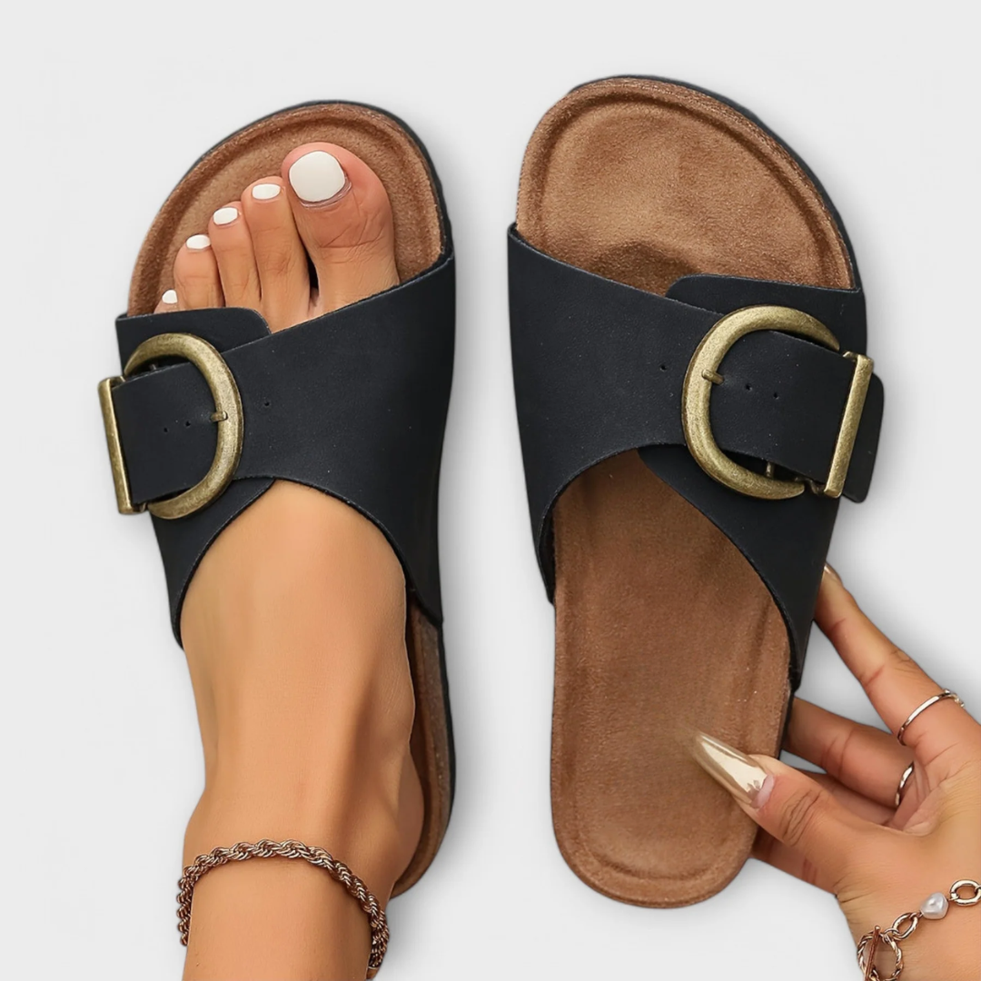 Orthopedic sandals in black with adjustable ankle strap and round buckle on a cork footbed.