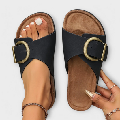 Orthopedic sandals in black with adjustable ankle strap and round buckle on a cork footbed.